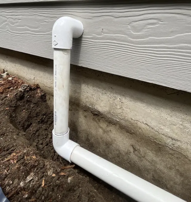 Sump pump discharge pipe routing water away from home foundation